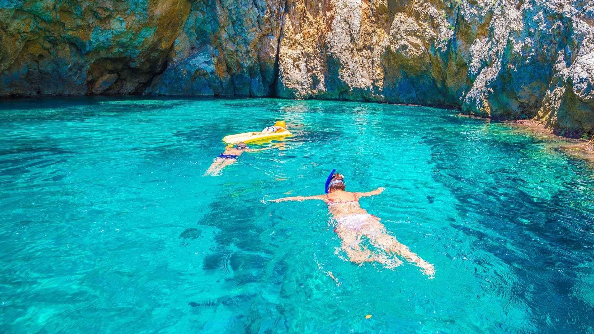 two people floating in the blue water greece